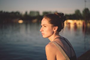 young woman thoughtfully staring over lake