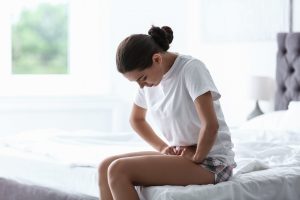 woman sitting on bed in pain